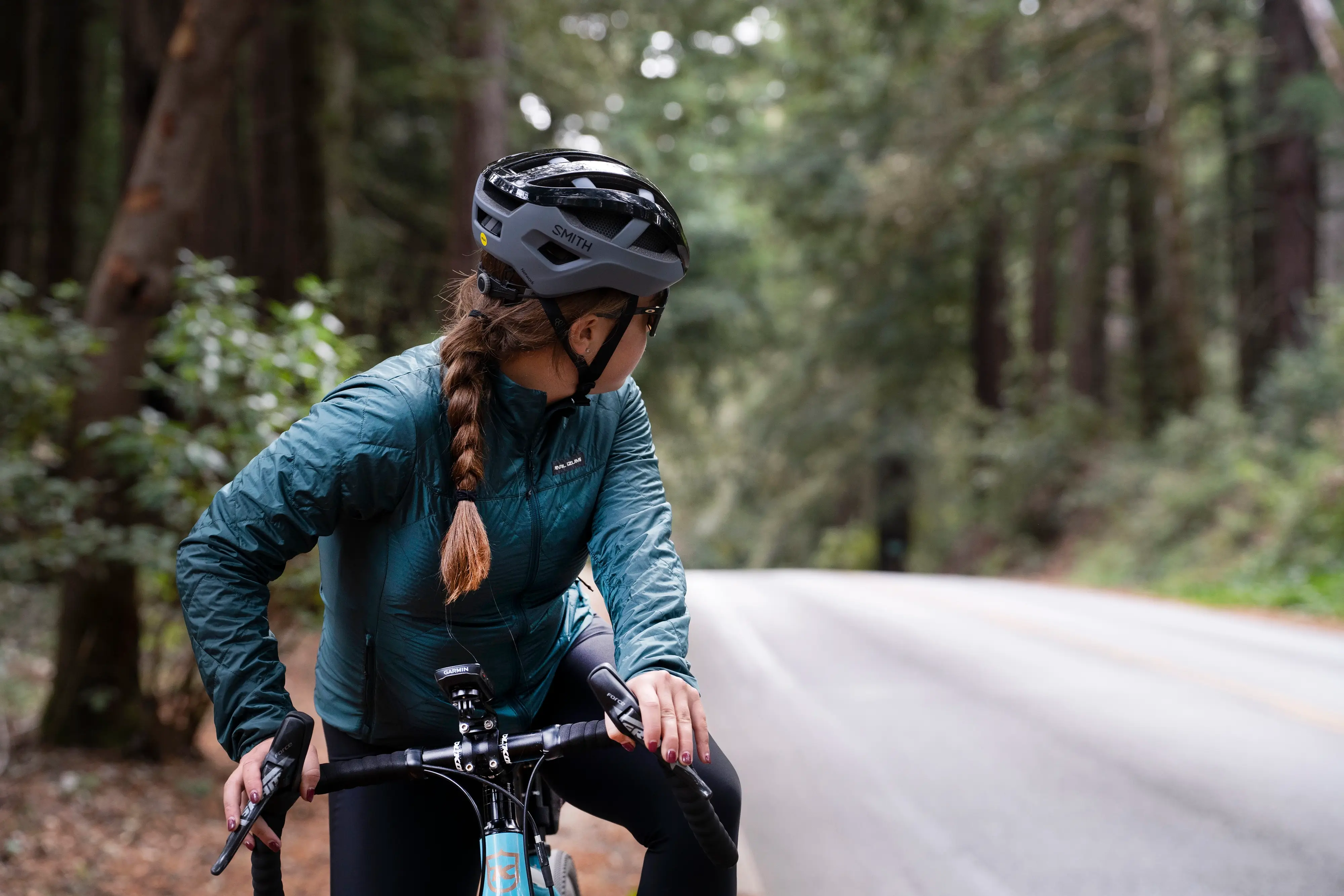 female cyclist wearing Pearl Izumi jacket and thermal bibs, taking a look back on the road