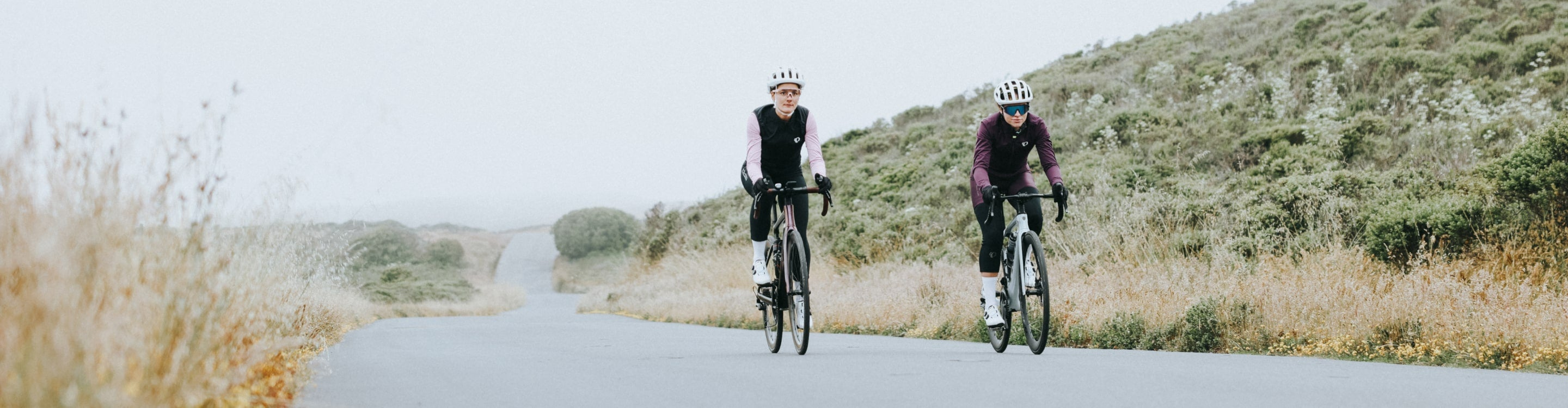 female cyclist wearing Pearl Izumi jacket and thermal bibs, taking a look back on the road