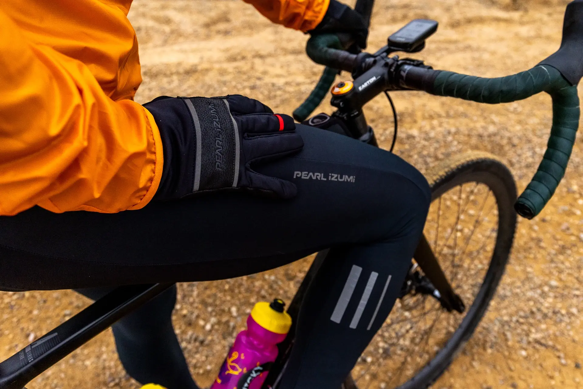 cyclist standing over bike, wearing Pearl Izumi thermal gloves and thermal bib tights