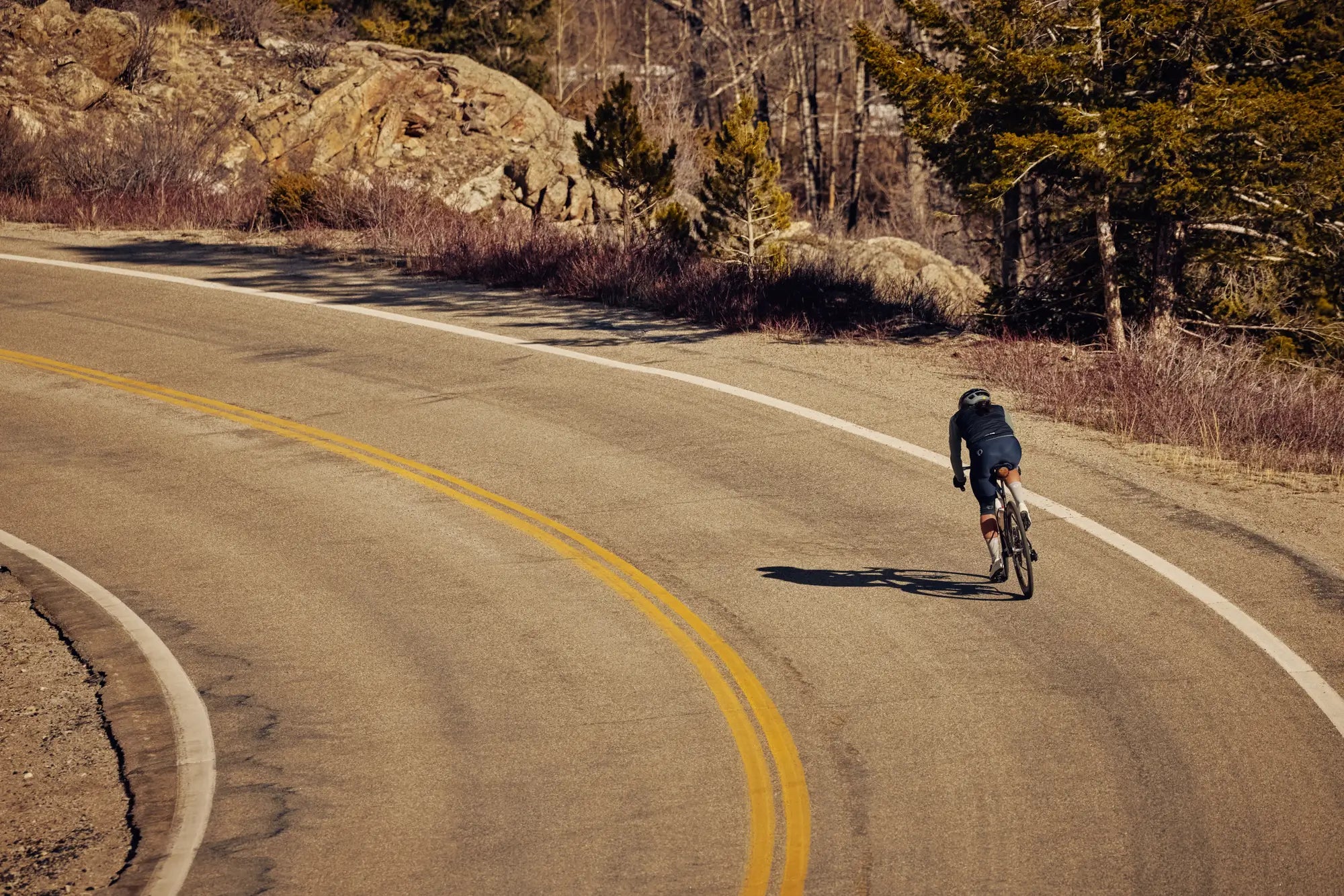 Cyclist riding on a winding road in the fall