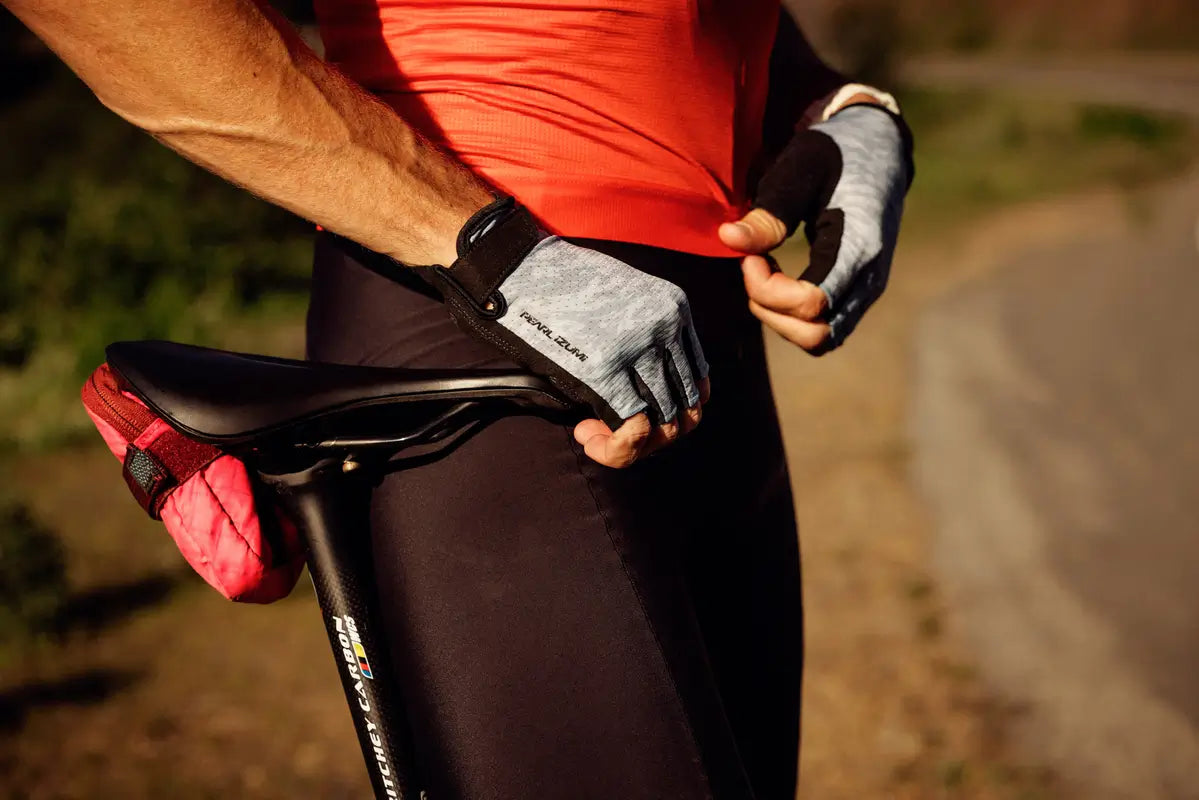 Person adjusting a bicycle seat with gloves on, outdoors.