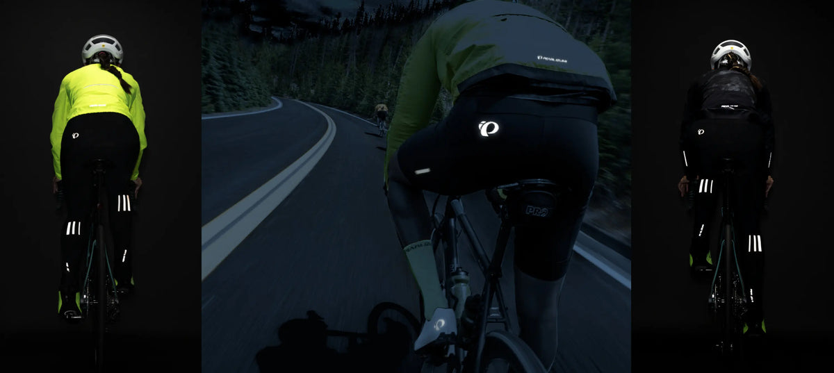 Cyclist in reflective gear on a dark road with helmet and jacket branding.