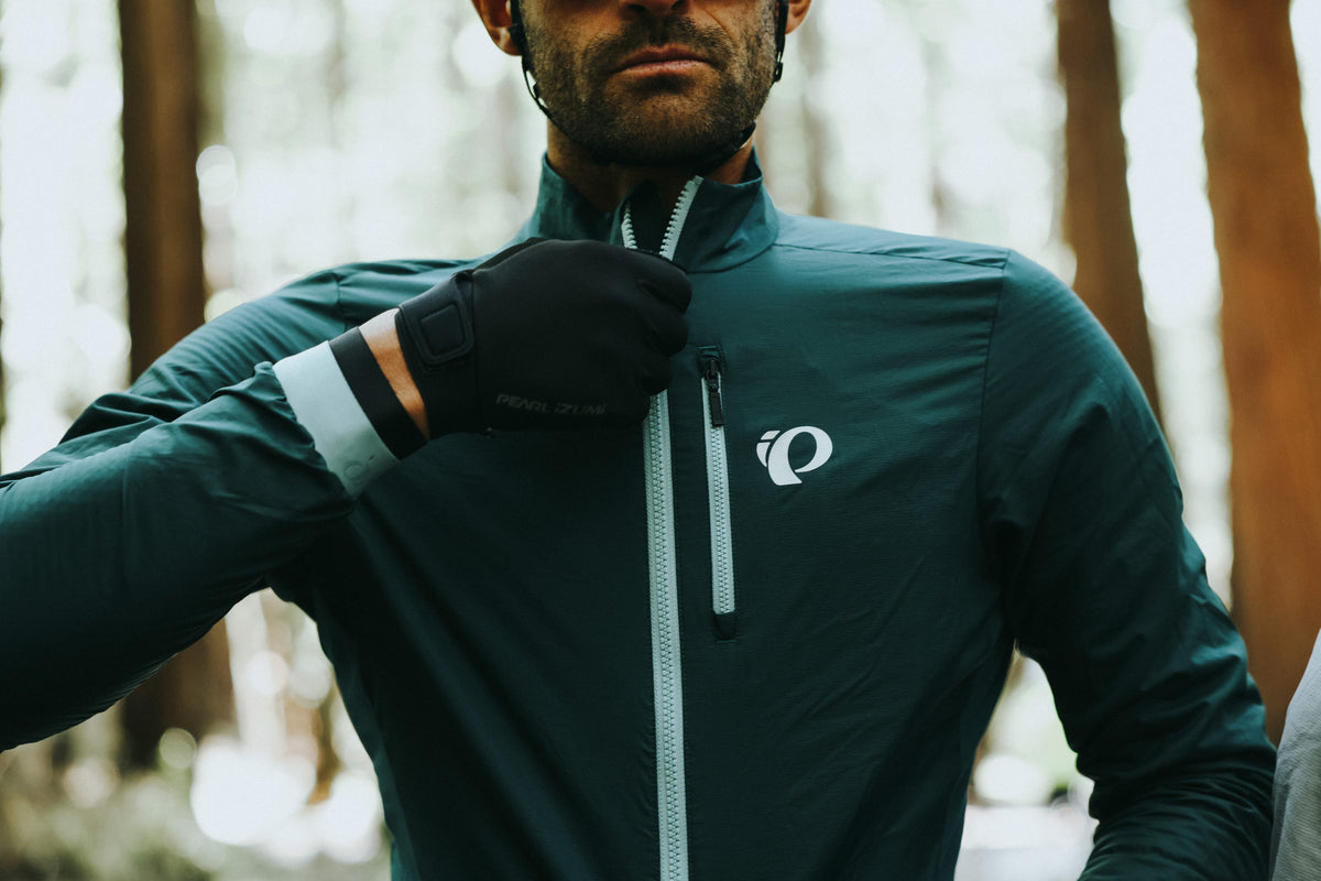 Close up image of male cyclist zipping up his green cycling jacket while wearing  cycling gloves for cool weather