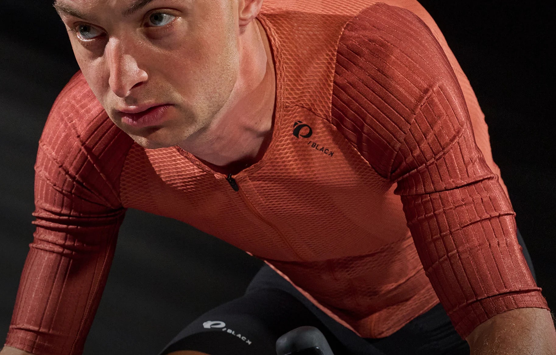 Person wearing a red cycling jersey with a brand logo on a dark background