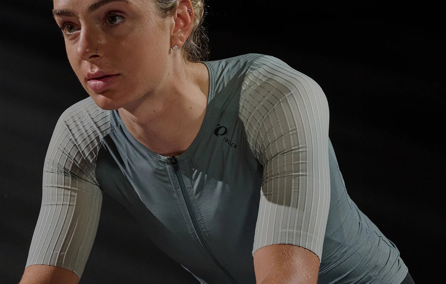 Person wearing a gray cycling outfit on a black background