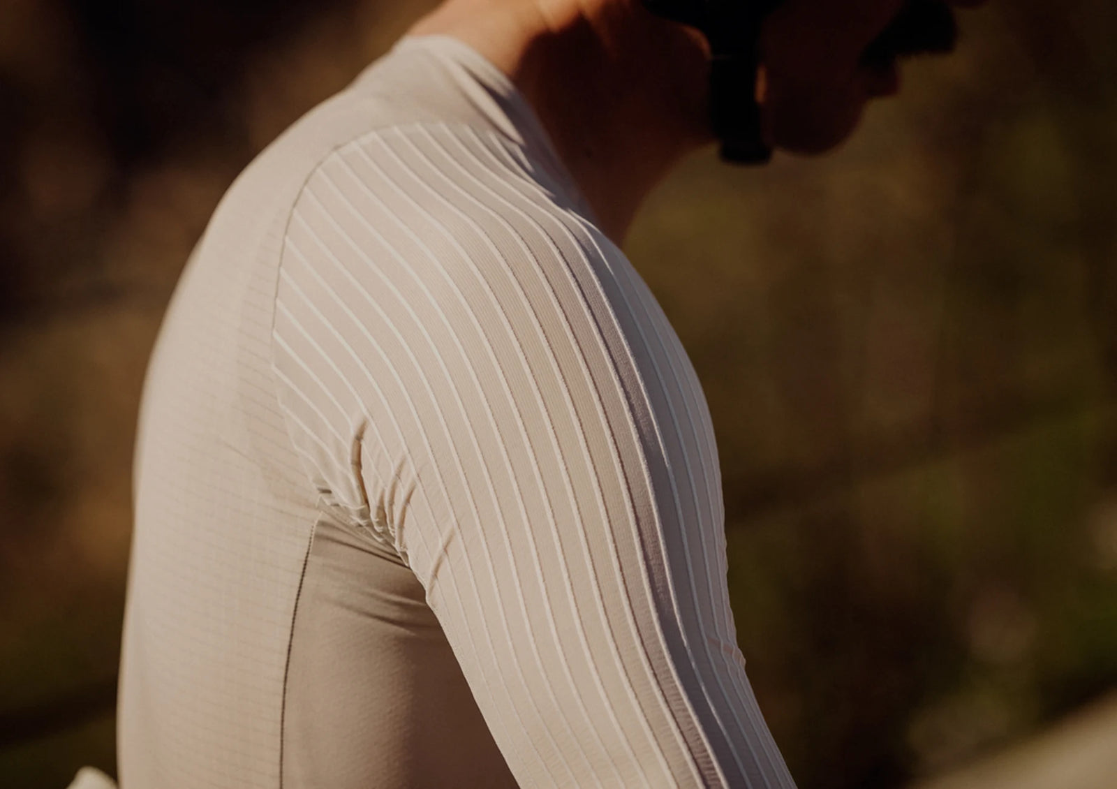 Close-up of a person wearing a beige long-sleeve top with a blurred background