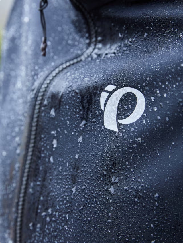 Close up image of a PEARL iZUMi cycling jacket shedding water droplets
